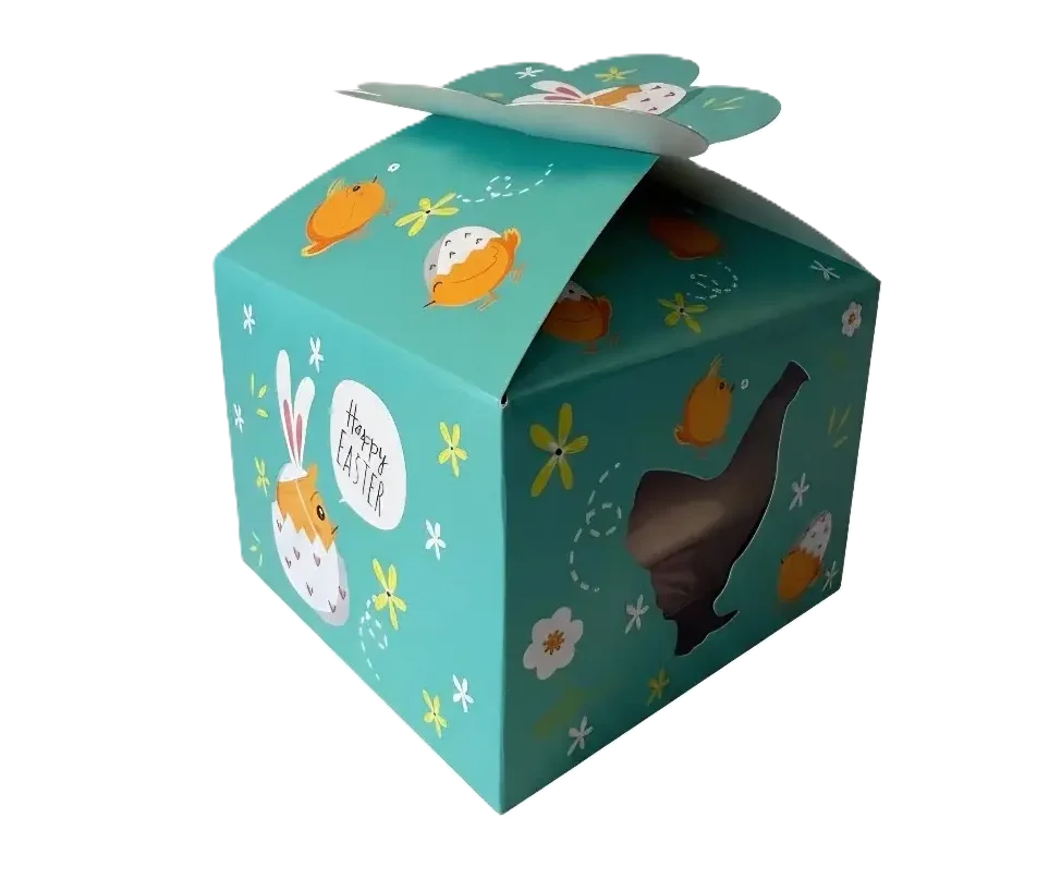 Lilia Oster-Geschenkbox mit gelben Küken, Blumen und 'Happy Easter'-Schriftzug, dazu ein seitliches Sichtfenster.