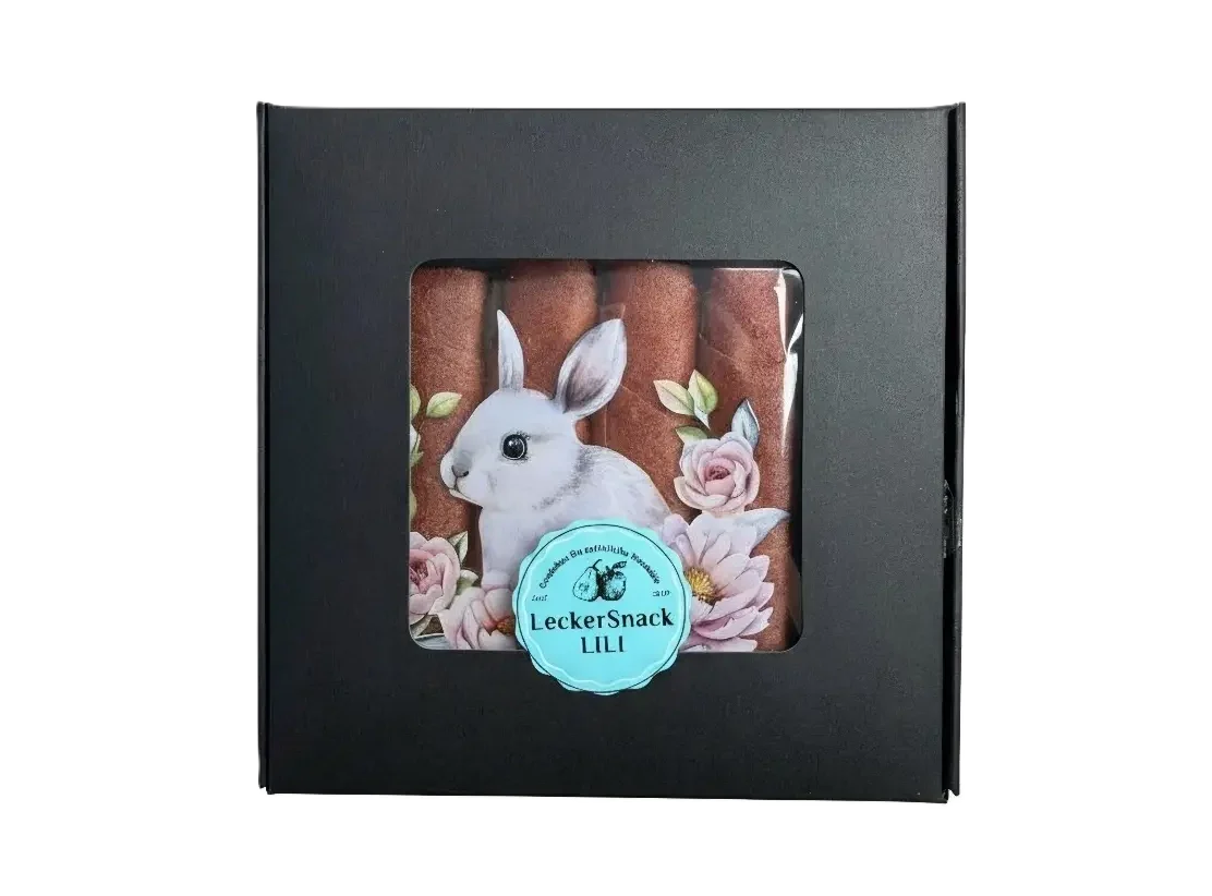 Oster-Fruchtleder-Rollen in kontrastreicher schwarzer Geschenkbox mit künstlerischen Hasen-Motiven und Blumen.