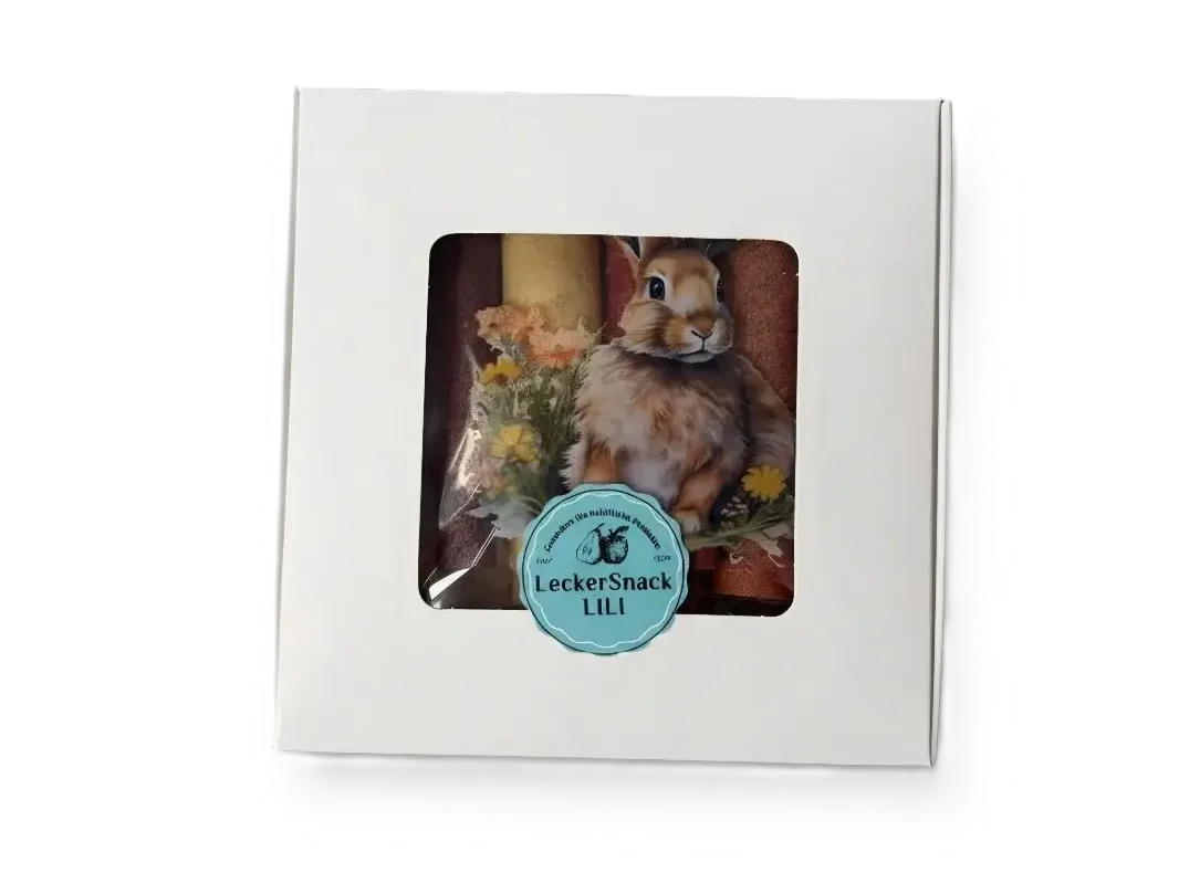 Oster-Fruchtleder-Rollen in kontrastreicher weißer Geschenkbox mit künstlerischen Hasen-Motiven und Blumen.