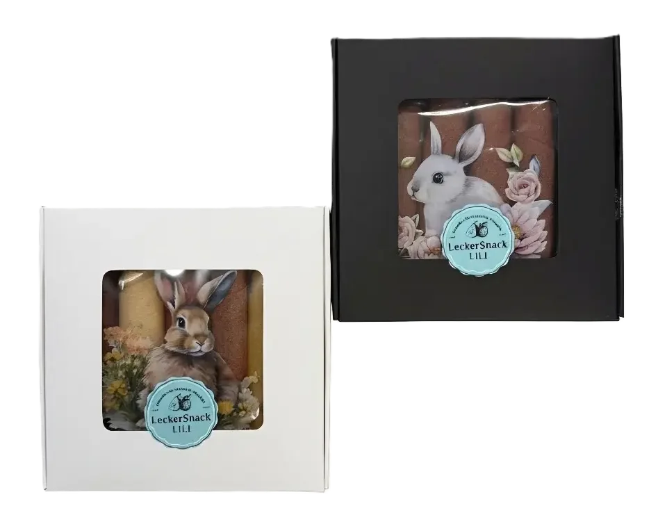Oster-Fruchtleder-Rollen in kontrastreicher weißer und schwarzer Geschenkbox mit künstlerischen Hasen-Motiven und Blumen.