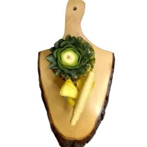 Hellgelbe Ananas-Fruchtlederrollen auf einem Holzbrett, umgeben von frischen Ananasstücken und Blättern.