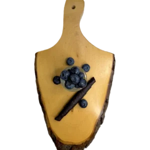 Eine dunkelviolette Heidelbeer-Fruchtlederrolle auf einem Holzbrett mit einer Schale frischer Blaubeeren.