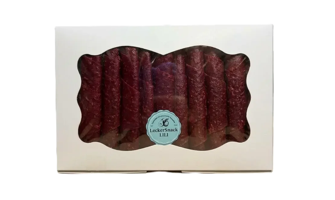 Weiße Geschenkbox mit Sichtfenster, gefüllt mit zahlreichen dunkelroten Himbeer-Fruchtleder-Rollen und Siegel.