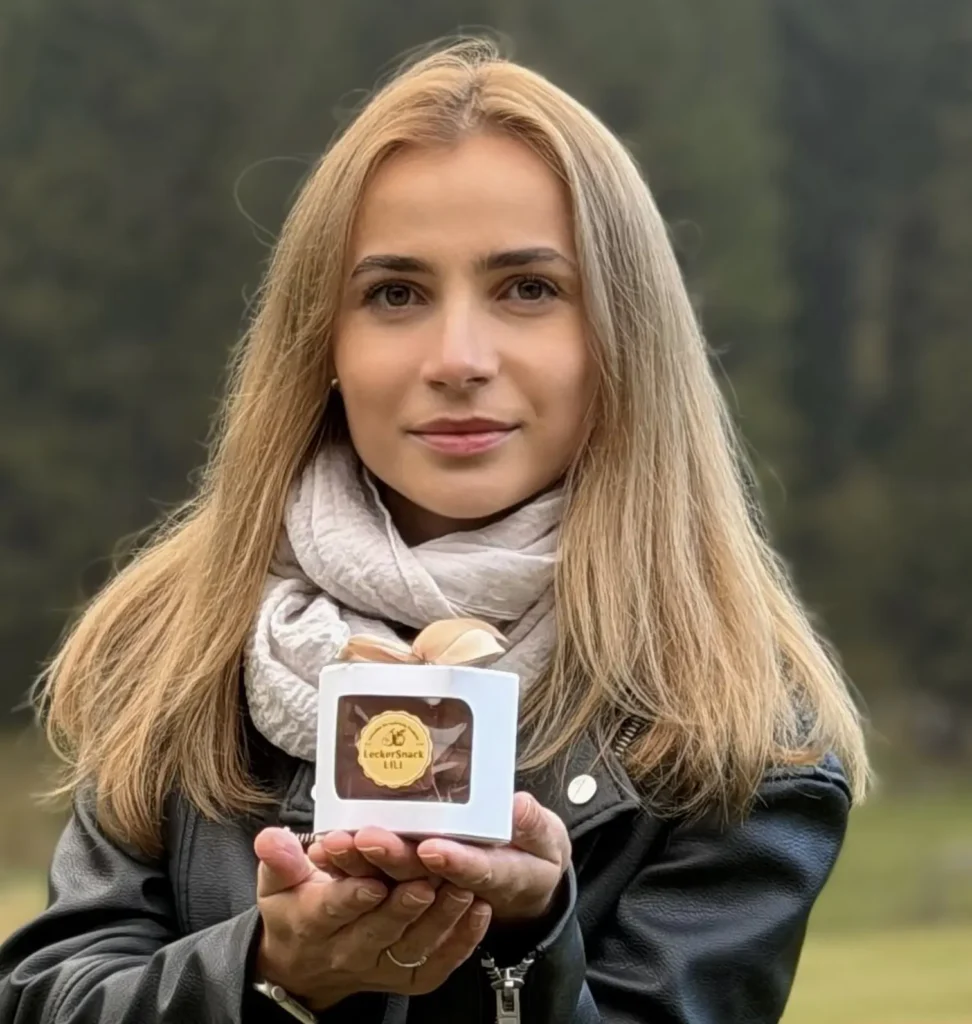 Liliia, Inhaberin von LeckerSnackLili, hält eine weisse Packung handgemachtes Schweizer Fruchtleder-Pastila.