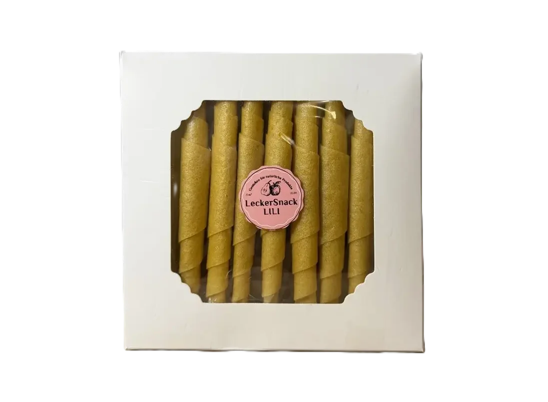 Weiße Fensterbox mit leuchtend orangen Fruchtleder-Rollen und rundem LeckerSnack Lili Siegel.