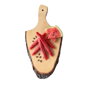 Vegane Wassermelone-Pastila-Fruchtleder Rollen serviert auf einem Holzschneidebrett mit frischen Wassermelonenscheiben und Kernen.